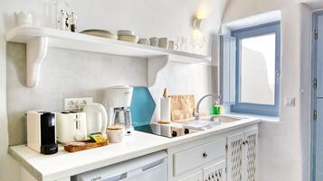 Una cocina moderna con armarios blancos, horno empotrado, cafetera y ventana con vistas.