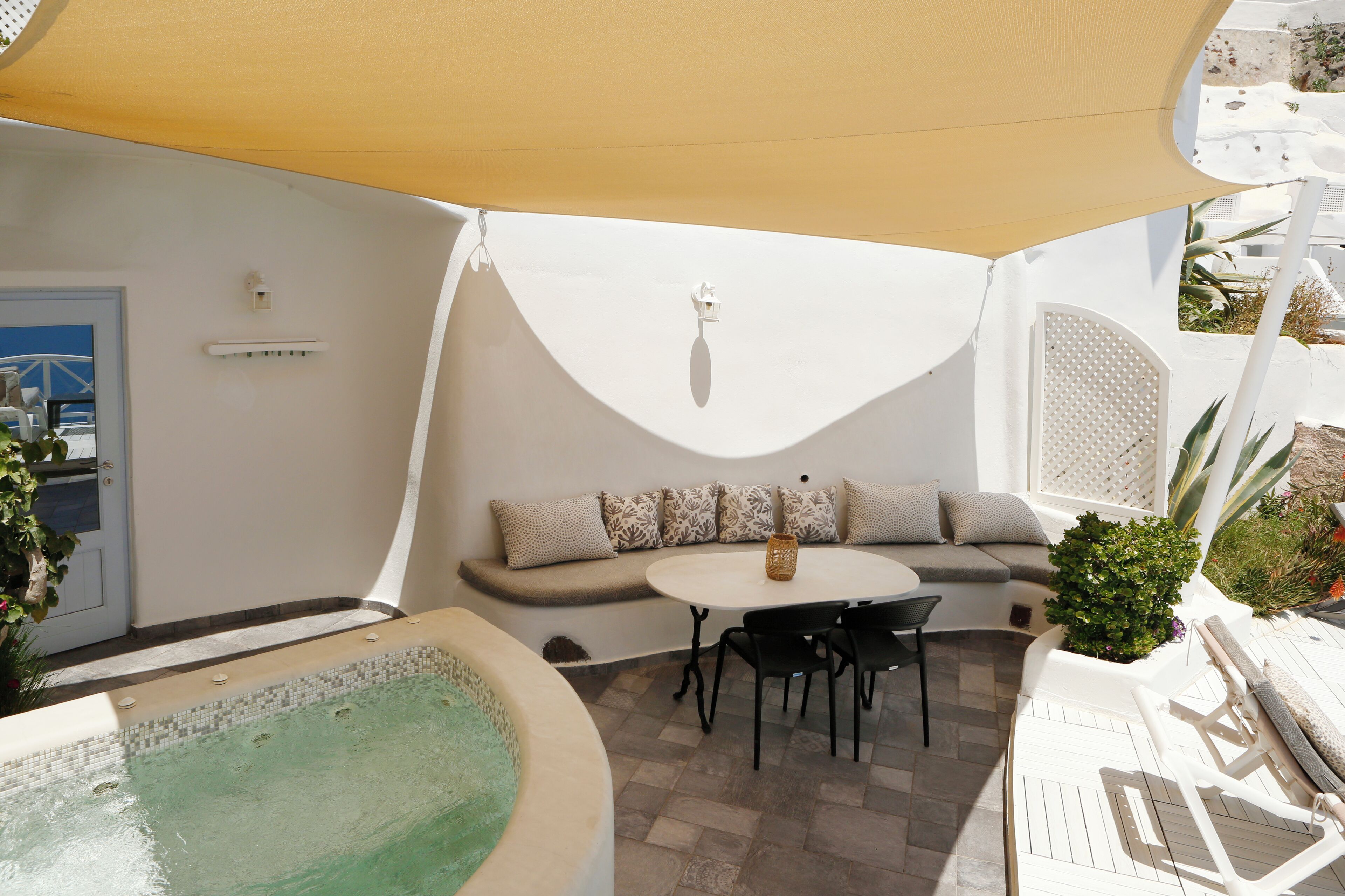 Un área de estar al aire libre con luz solar, una piscina, una mesa y sillas.