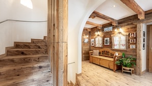 Una escalera de madera que lleva a una habitación con un banco de madera, una planta y cuadros en la pared.