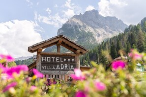 Un letrero de madera del Hotel Villa Adriat, con montañas al fondo.