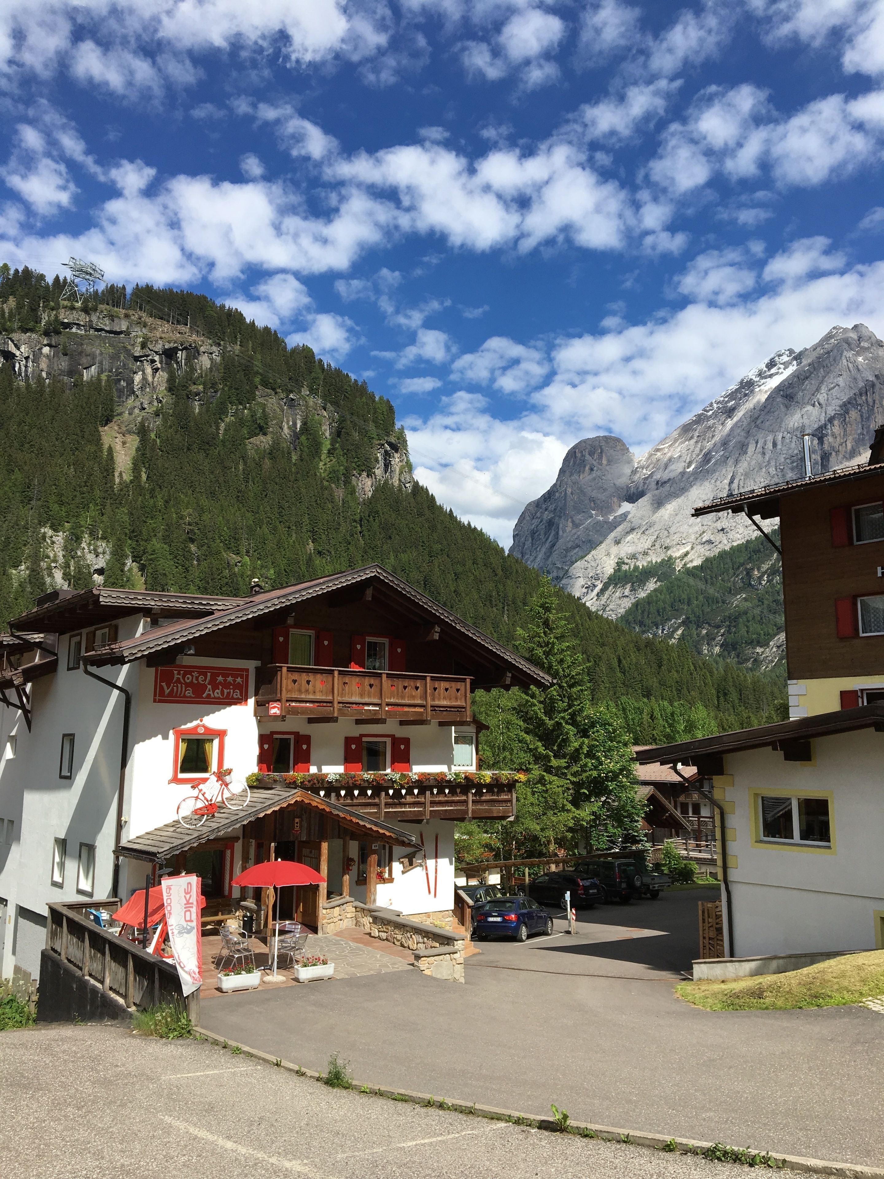Un rifugio di montagna con un balcone, una bicicletta rossa e un cartello con la scritta 'Hotel Villa Adria'.