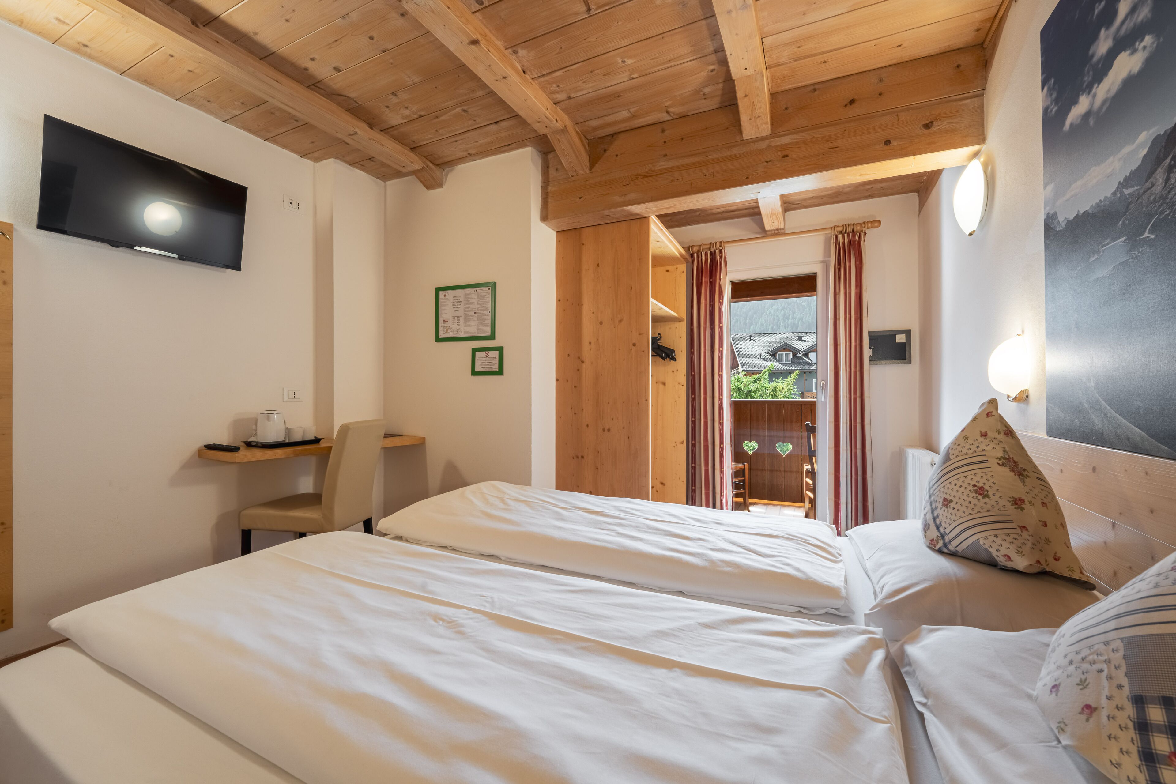 Ein Schlafzimmer mit zwei Betten, einem Schreibtisch und einem Fernseher.