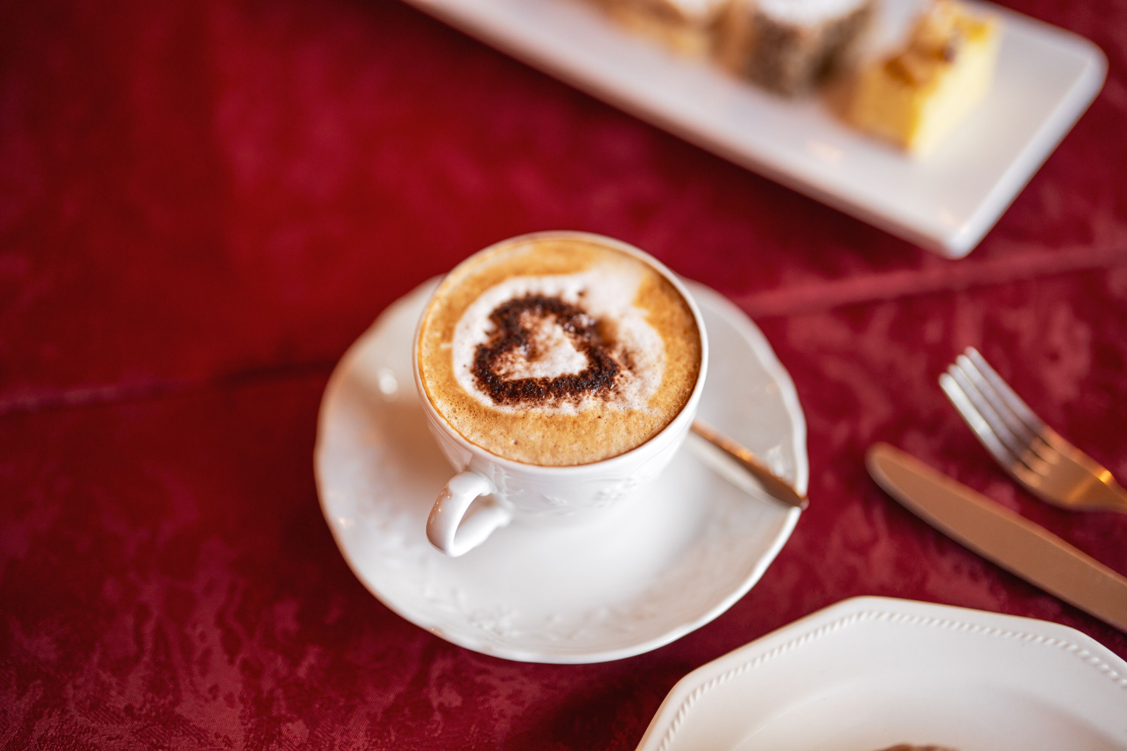 A cup of coffee with a heart-shaped design on the foam, placed on a white saucer.