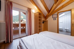 Un dormitorio con cama, armario de madera y puerta corrediza de vidrio que da a un balcón.