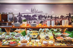 A buffet with various food items and beverages, with a cityscape backdrop. - Hotel Charles Central - Czech Leading Hotels (Prague)