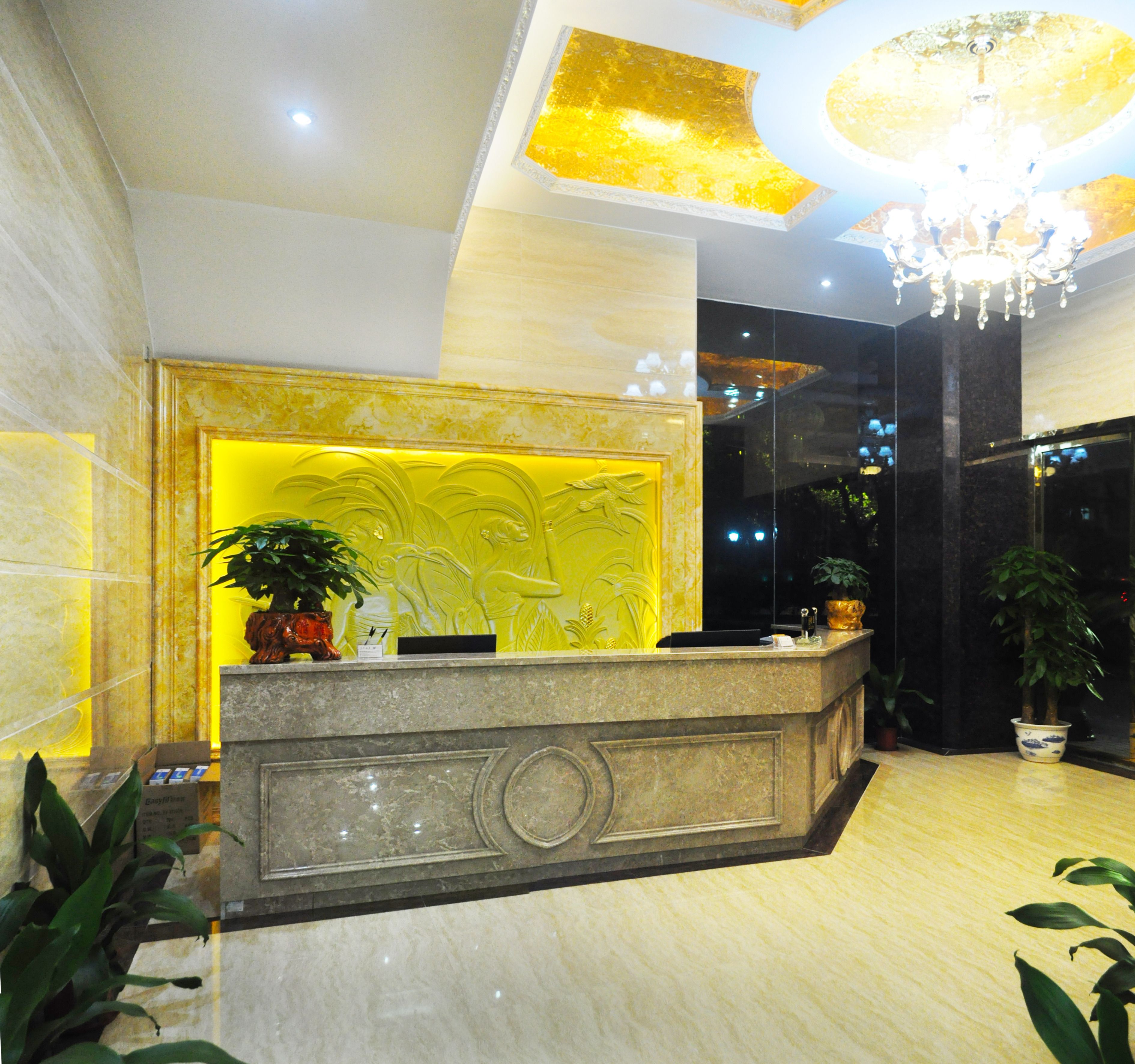 A reception desk with a marble counter, a chandelier, and potted plants.