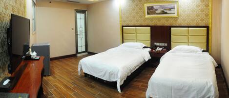 A hotel room with two beds, a wooden floor, a TV, and a painting on the wall.