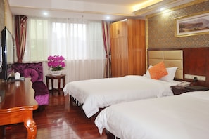 A hotel room with two beds, a wooden desk, a chair, and a vase with flowers. - Jingdu Hotel (Guangzhou)