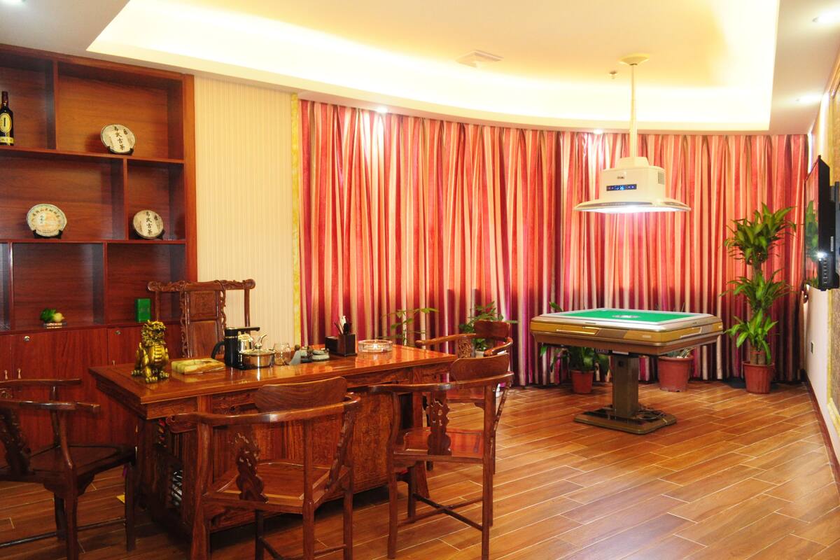 A wooden dining table with chairs, a pool table, and a ceiling fan in a room with striped curtains and wooden shelves.