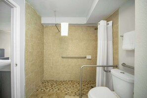 Ein Badezimmer mit Dusche, Toilette und Haltegriff.