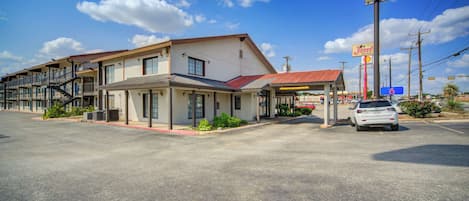 Un motel con techo rojo, un estacionamiento y un letrero que indica el número 6.