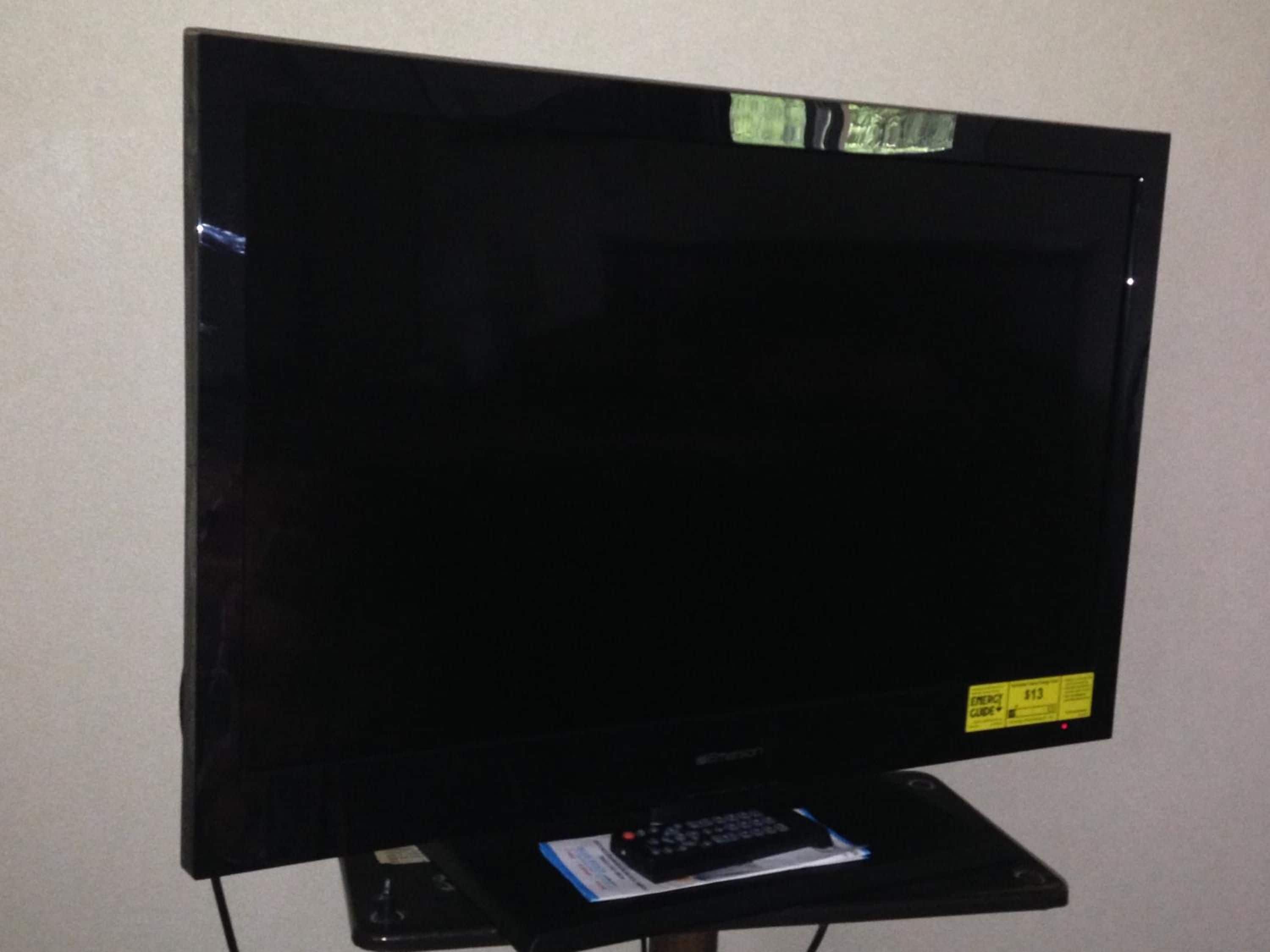 A flat-screen television on a stand with a remote control.