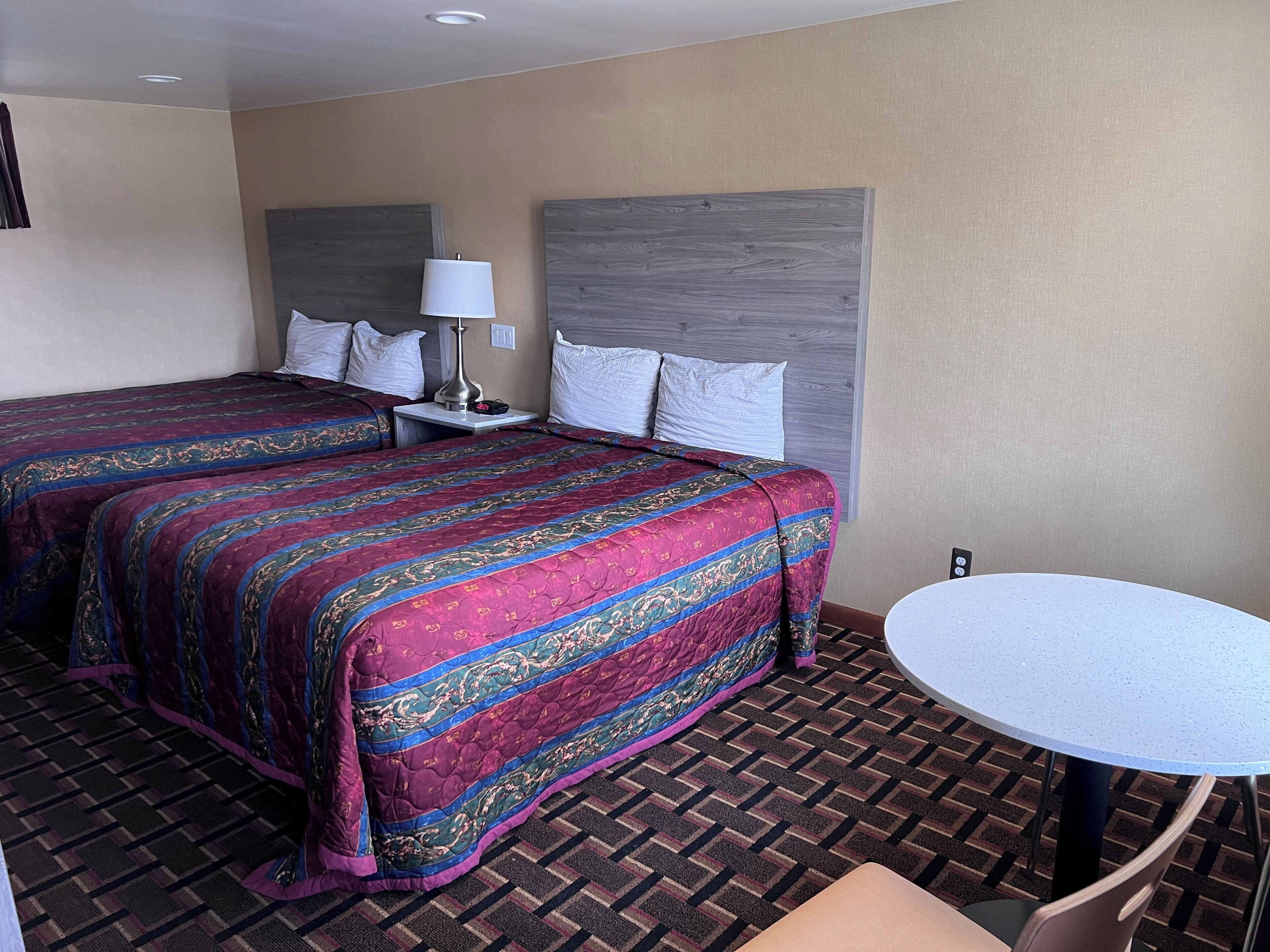 Une chambre d’hôtel avec deux lits, une table ronde et une chaise.
