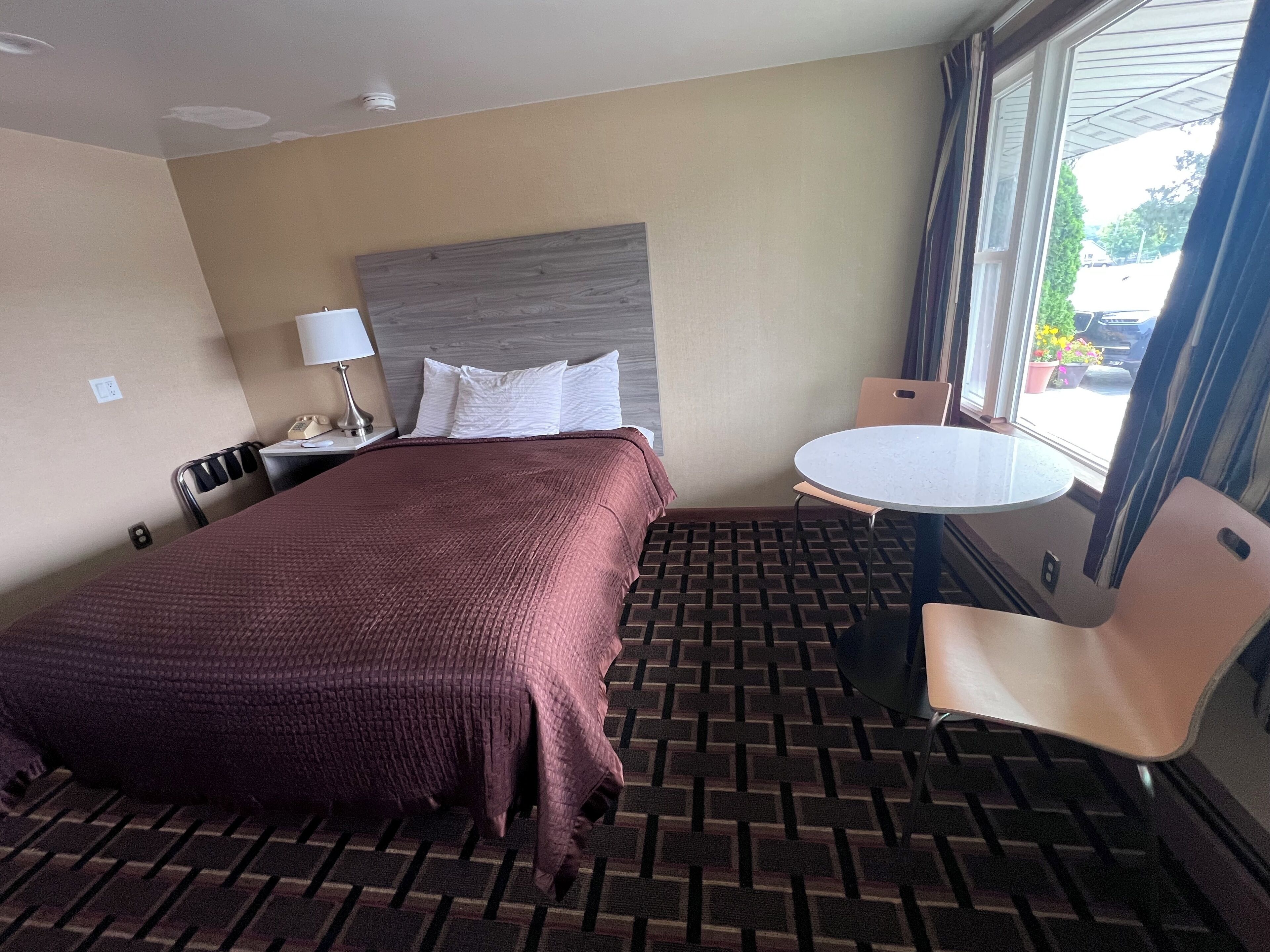 Une chambre d’hôtel avec un lit, un bureau doté d’une lampe, une table ronde et une chaise.