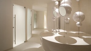 Une salle de bain moderne avec un grand lavabo incurvé et plusieurs miroirs.