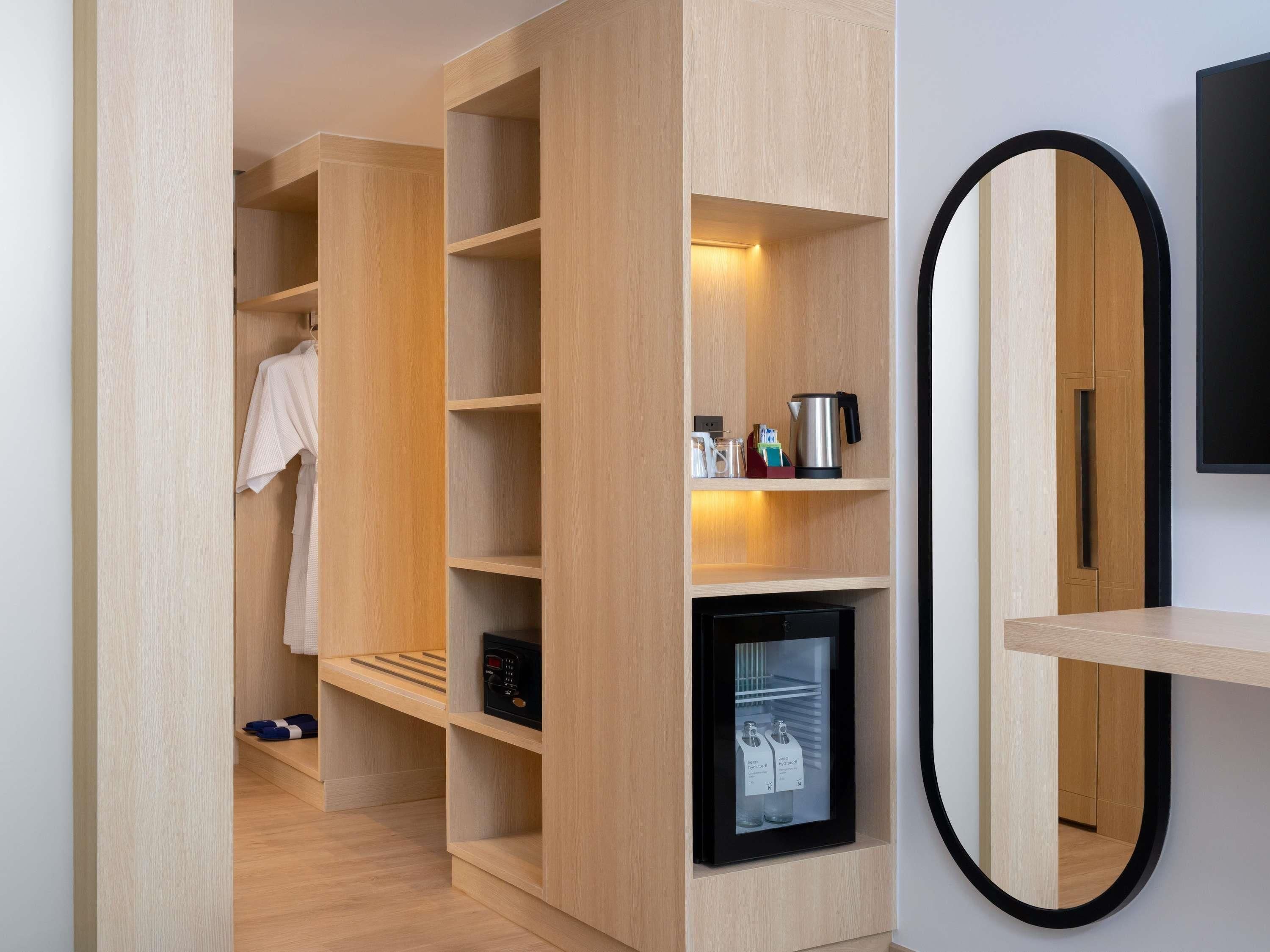 A modern room with built-in wooden shelving, a small black-framed television, and a mirror.