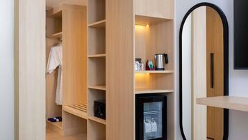 A modern room with built-in wooden shelving, a small black-framed television, and a mirror.