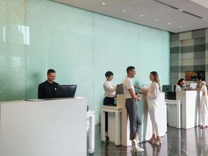 A reception area with a modern design, featuring a glass wall, a reception desk, and a seating area. - Novotel Bangkok Platinum Pratunam (Bangkok)
