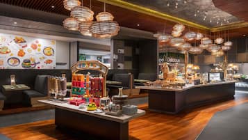 A modern restaurant interior with a central dining area, multiple hanging light fixtures, and a colorful wall mural.