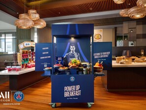 A breakfast area with a 'Power Up Breakfast' station featuring a variety of food items and a poster with a sports theme. - Novotel Bangkok Platinum Pratunam (Bangkok)