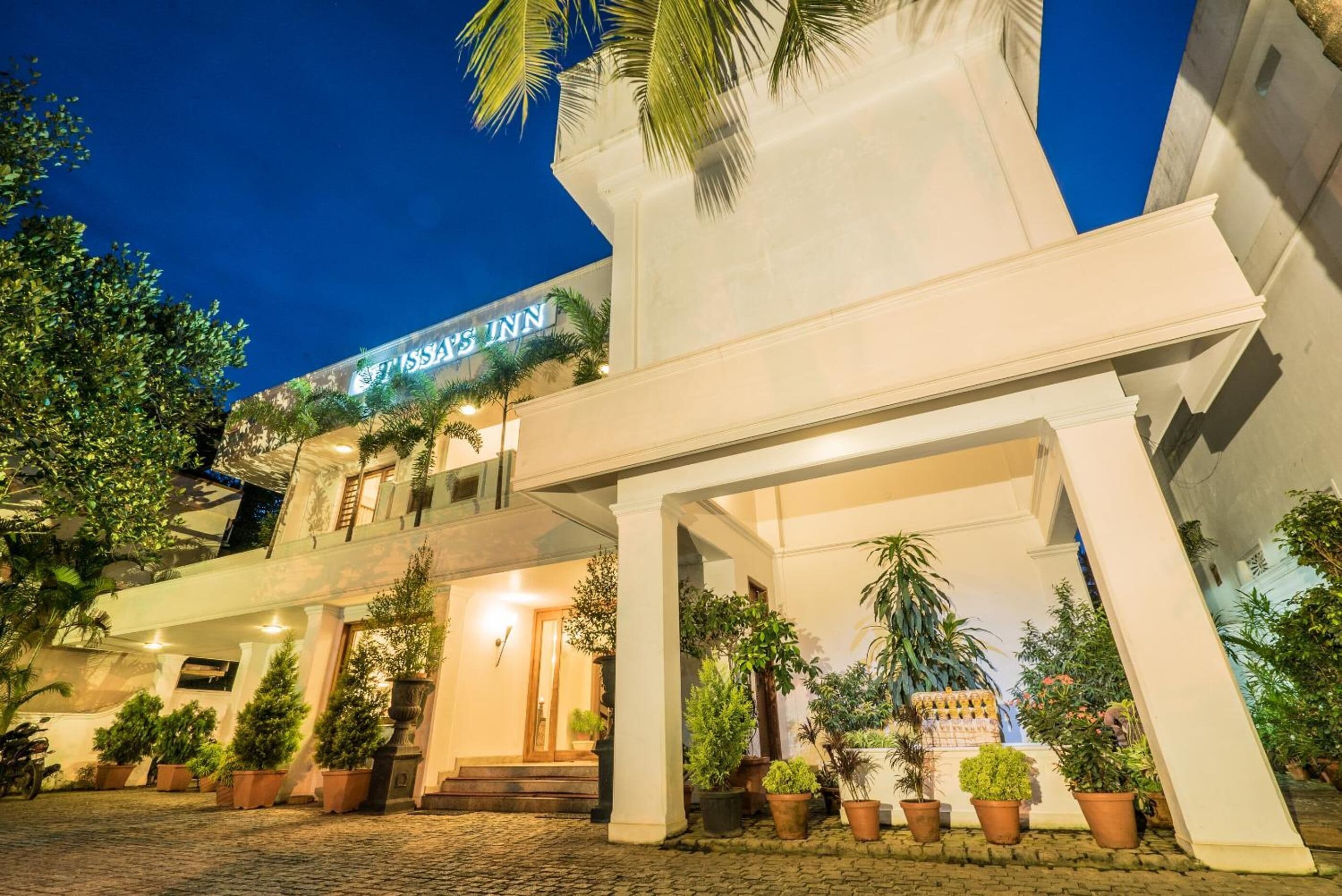 Entrada de un hotel con un letrero que dice "HISSA'S INN" y un área exterior cubierta con plantas en macetas.