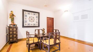 Un comedor con una mesa y sillas de madera, un aparador decorativo, una obra de arte floral enmarcada y una puerta de madera.