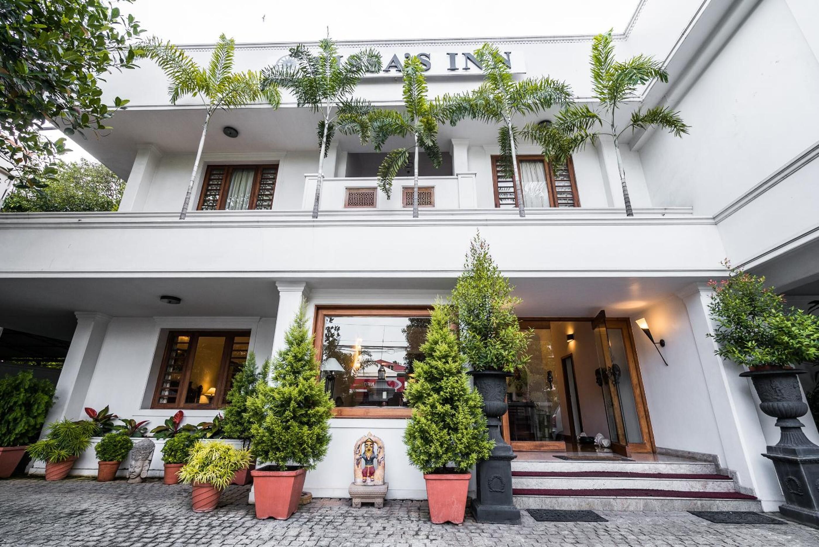 A hotel entrance with a sign reading "Hotel's Inn," potted plants, and a statue.