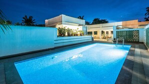 A swimming pool with a clear blue water surface, surrounded by a white wall and a green fence. - Tissa's Inn (Kochi)