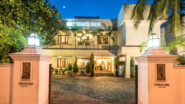 Tissa's Inn with a cobblestone entrance, potted plants, and a sign above the entrance. - Tissa's Inn (Kochi)