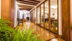 A hallway with wooden beams, a polished floor, and a dining area visible through glass doors. - Tissa's Inn (Kochi)