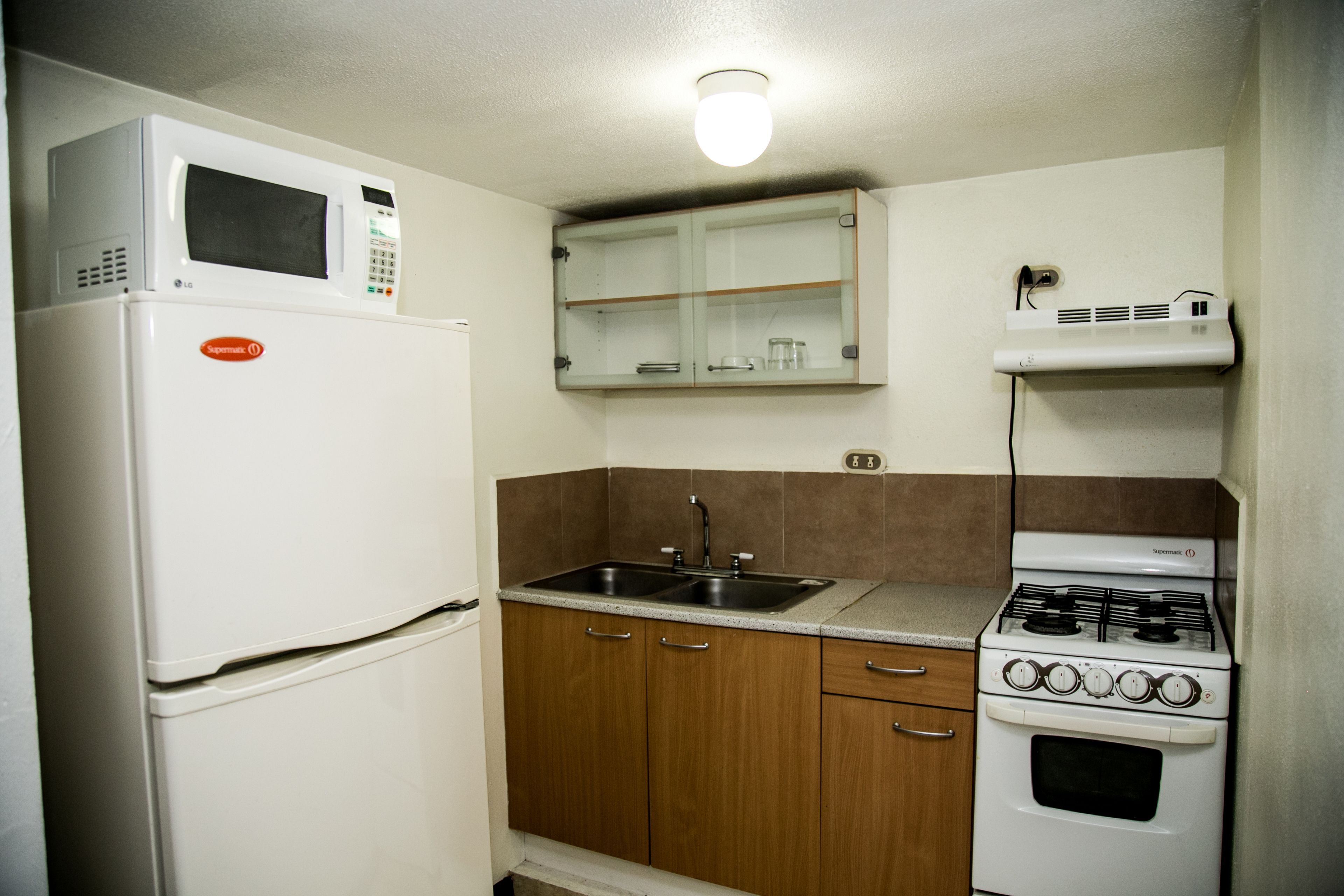 Une cuisine compacte équipée d’un réfrigérateur, d’une cuisinière, d’un évier et d’un four à micro-ondes.