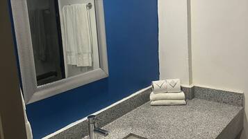 A bathroom with a blue wall, a white sink, a mirror, and a towel rack.