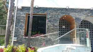 A modern building with a stone facade, a large window, and a staircase leading to an upper level. - Suites DIOH (Monterrey)