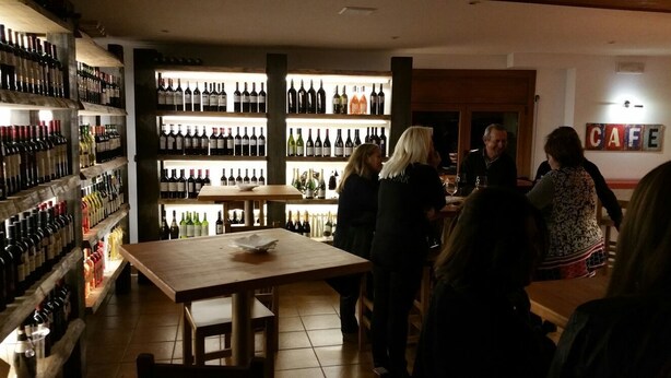 Una bodega con estantes llenos de botellas de vino y una mesa de madera en el centro.