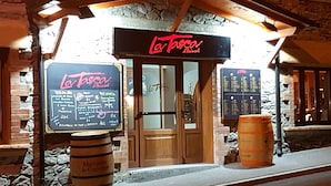 Un restaurante llamado "La Tasse" con un menú en pizarra, barriles de madera y paredes de piedra.
