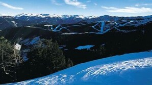 Paisaje montañoso con picos nevados y cielo azul despejado.