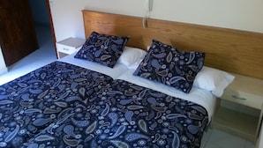 Una cama doble con cabecera de madera, dos mesitas de noche y una colcha estampada.