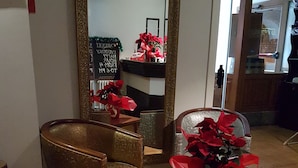 Una habitación con un espejo grande, una silla y una mesa adornada con un lazo rojo.