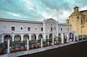 A historic building with a central archway, flags, and a fountain.