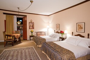 A hotel room with two beds, a dining table, a chair, a lamp, and a painting on the wall. - Dann Monasterio Popayan (Popayán)