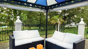 Relax in a serene garden setting with comfortable seating and a small table.
