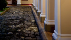 A courtyard with a cobblestone path, white columns, and arched doorways. - Hotel Dann Monasterio Popayán (Popayán)