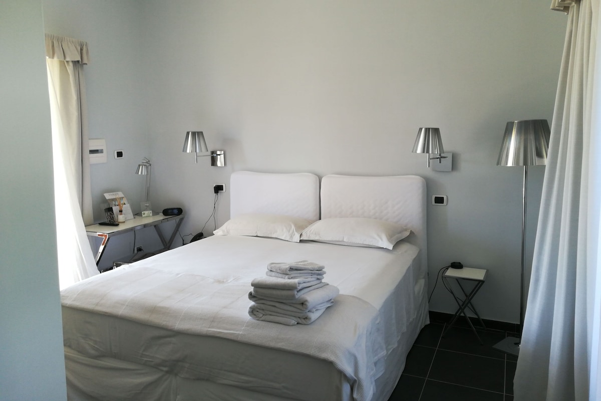 A neatly arranged hotel room with a large bed, two bedside lamps, a small desk, and a floor lamp.