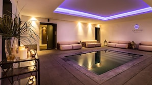 A spa area with a large heated pool, multiple seating areas, and ambient lighting. - La Suite Boutique Hotel (Procida)