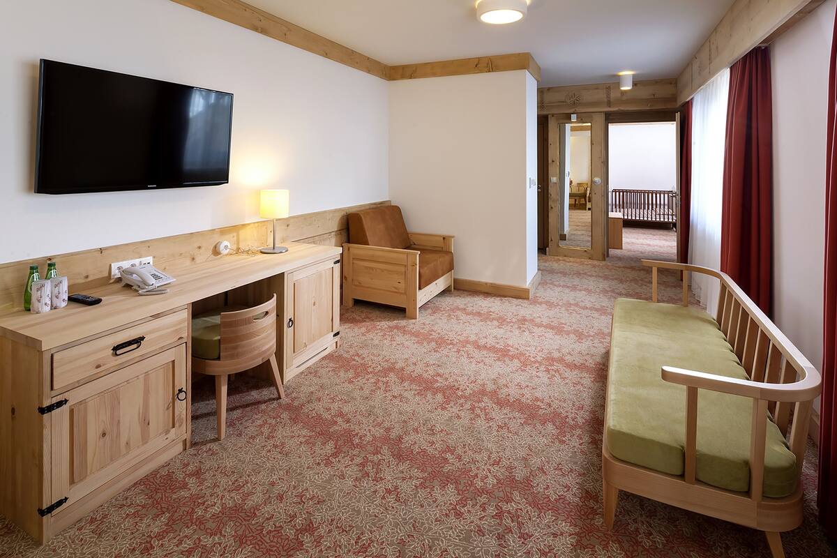 Une chambre d’hôtel équipée d’une télévision à écran plat, de meubles en bois, d’un petit bureau et d’un berceau.