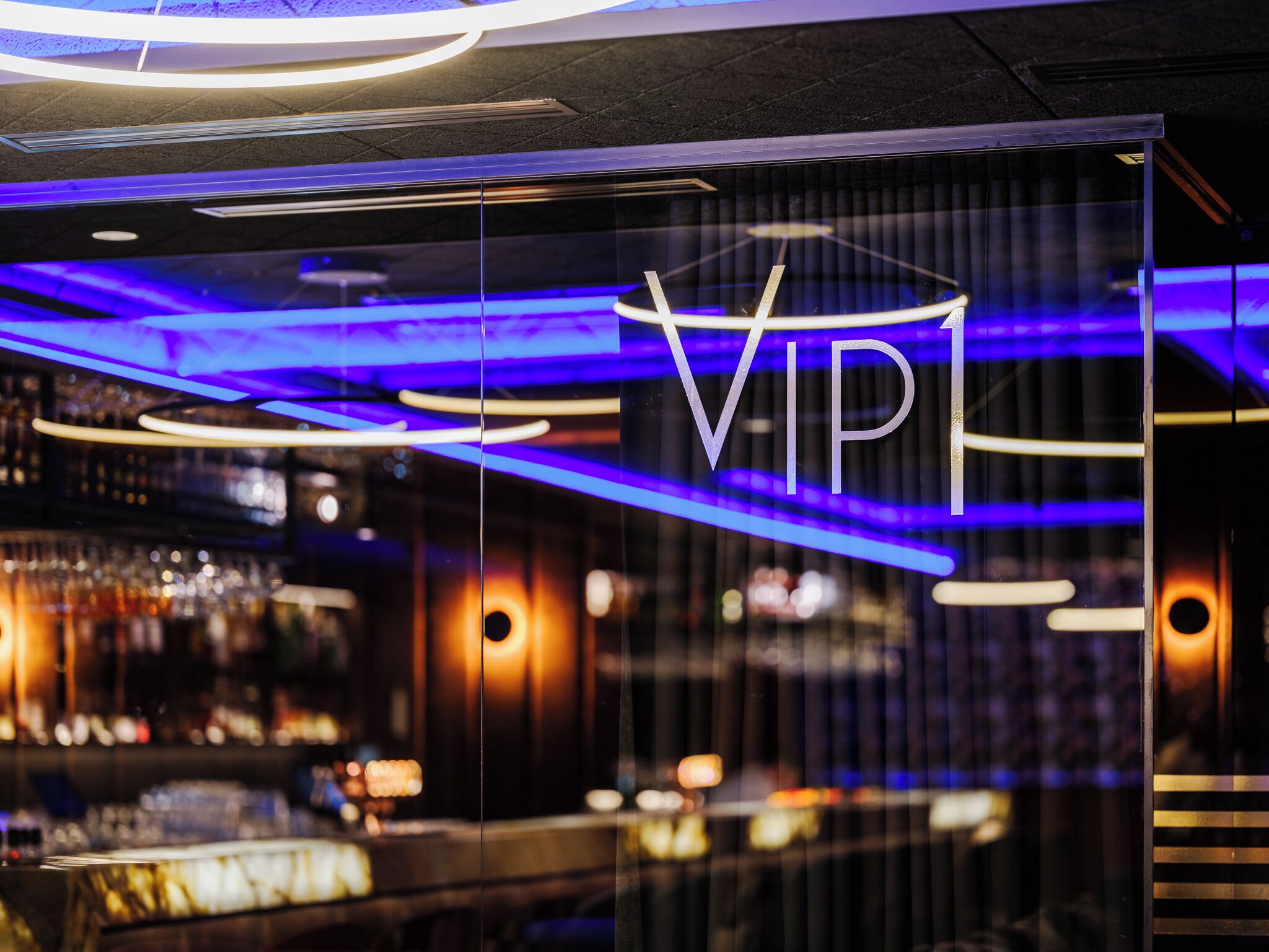 A modern interior with a VIP sign, ambient lighting, and a bar area.