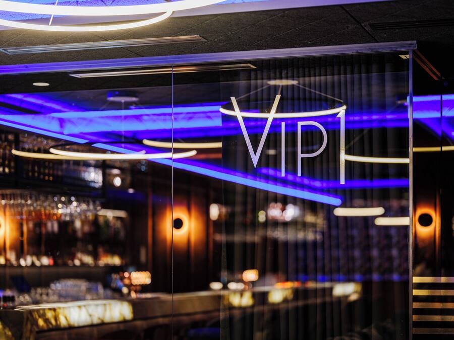 A modern interior with a VIP sign, ambient lighting, and a bar area.
