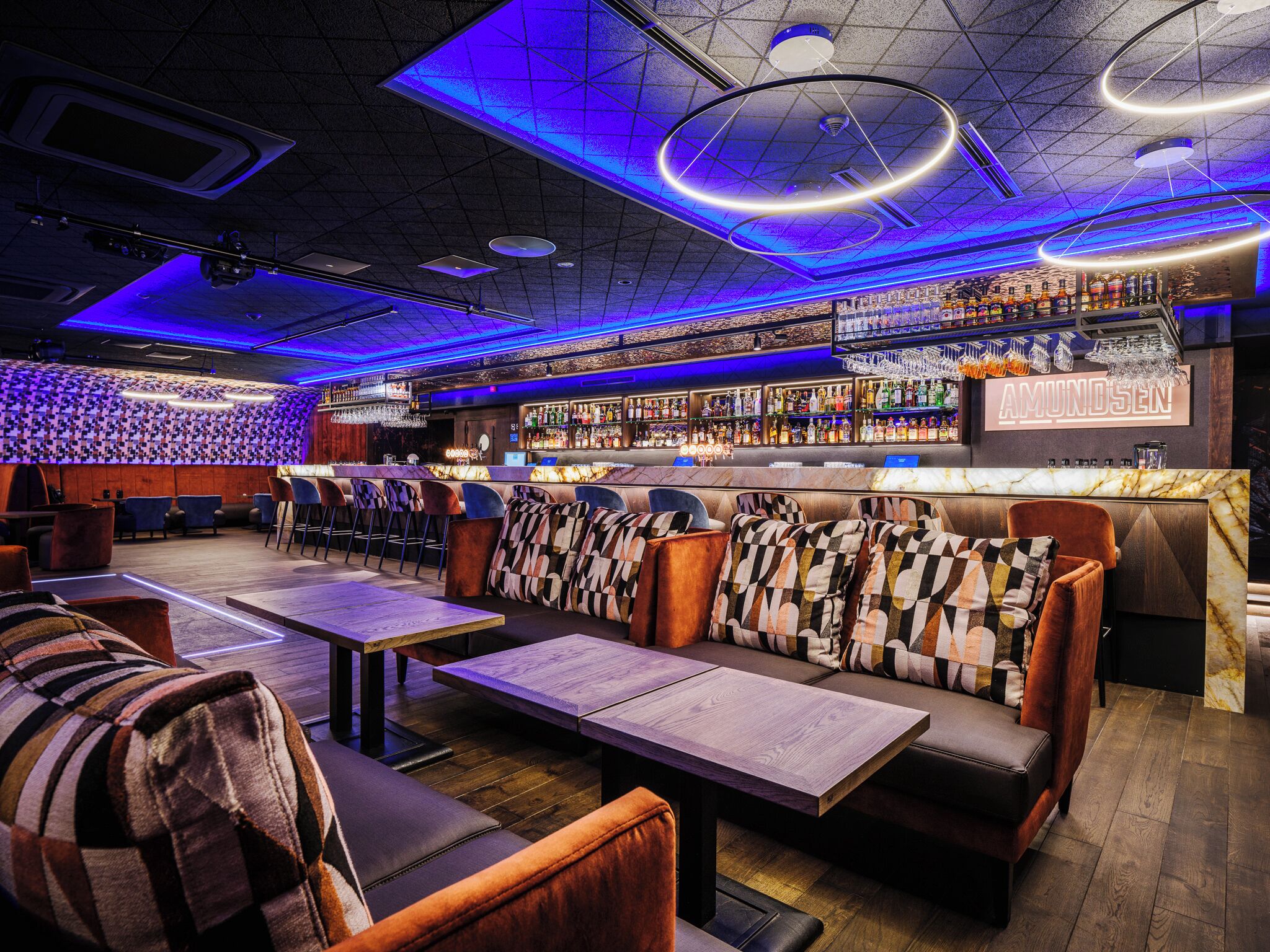 A bar with a modern design, featuring a mix of seating options including bar stools and cushioned chairs.