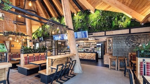 A restaurant with wooden tables and benches, a green wall with plants, and a menu board. - Hotel Bania Thermal & Ski (Bukowina Tatrzanska)