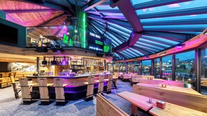 A modern bar area with wooden furniture, a bar counter, and a large glass ceiling. - Hotel Bania Thermal & Ski (Bukowina Tatrzanska)